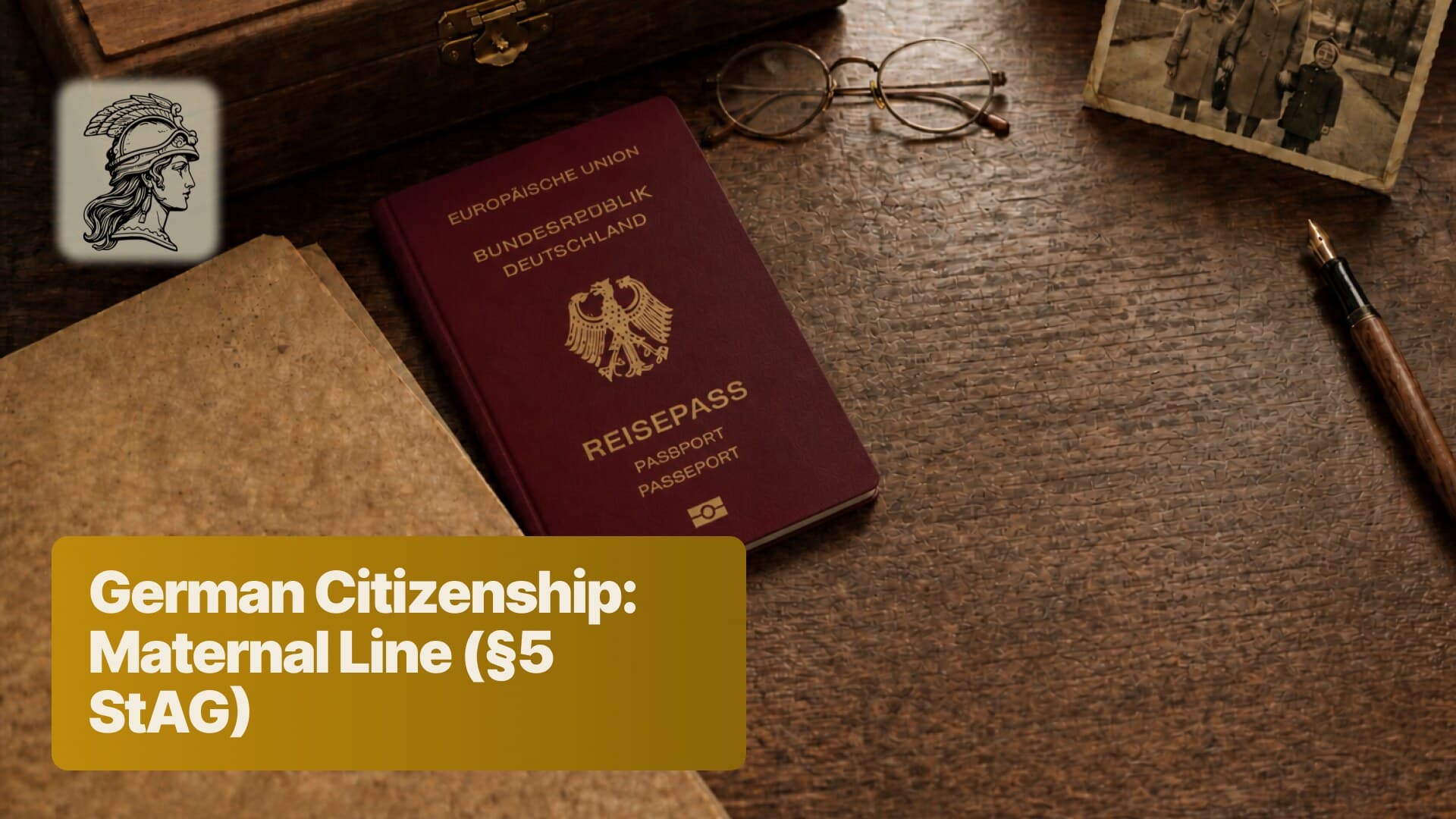 A German passport on a dark desk beside reading glasses, a blank sheet of paper, a wooden document box and a sepia family photograph - the maternal line under §5 StAG